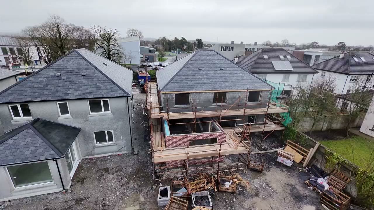 Vue aérienne de maisons en rénovation, toits d'ardoise neufs et échafaudage le long de la façade