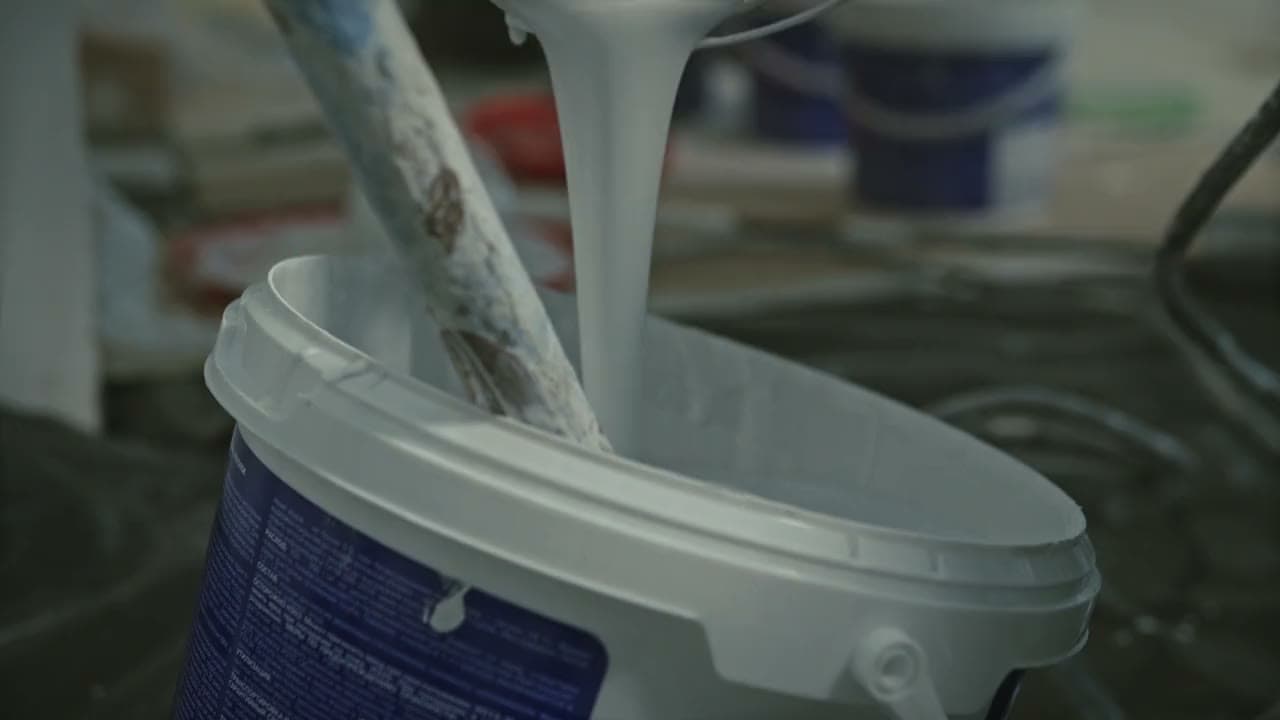 Paint being poured and mixed in a bucket, ready to apply