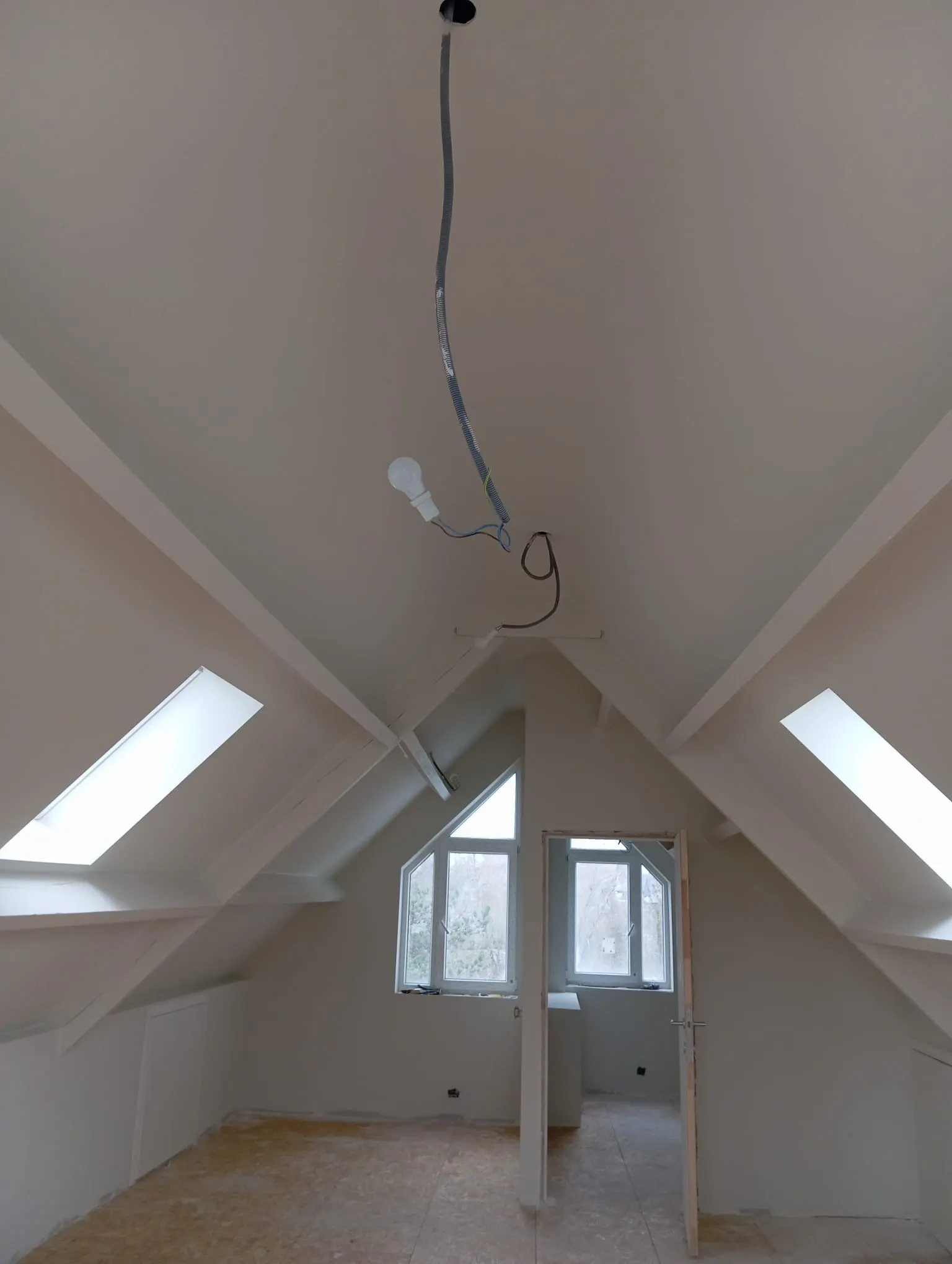 Attic space painted entirely white, with an exposed ridge beam and two roof windows