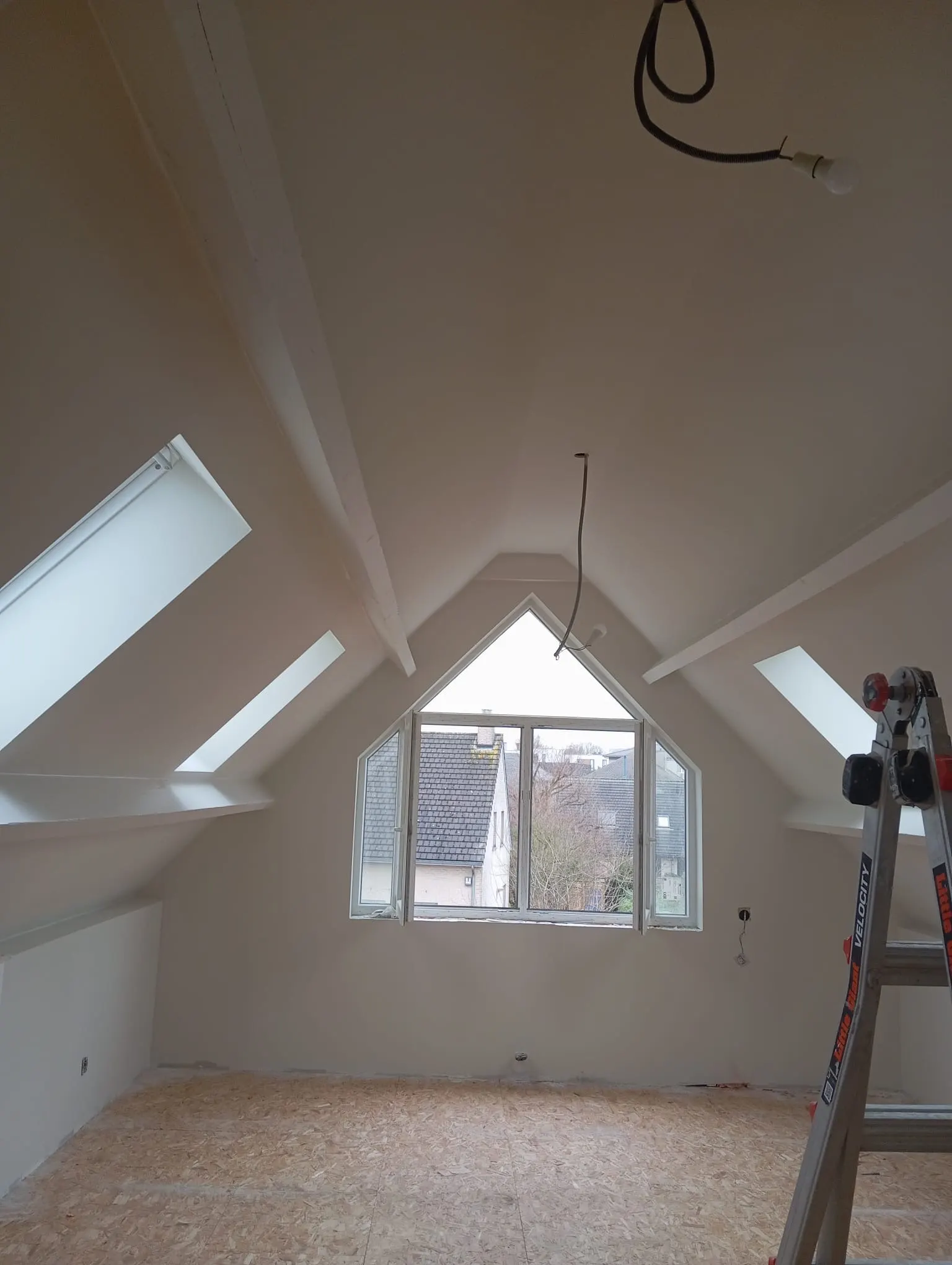 Painted attic room with a gable window and two roof windows, ladder against the wall