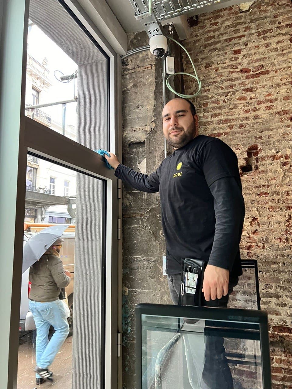 Glazenwasser Dobicleaning lacht bij een raam in Antwerpen